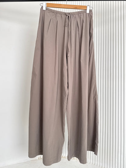 Wide leg pants by Amenaa featuring a relaxed fit, high waist, and flowing fabric, shown in a neutral color.
