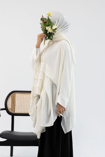 Amenaa ruffles blouse featuring layered fabric and soft pastel color, displayed on a hanger against a neutral background.