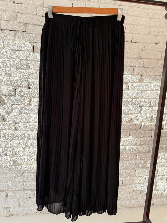 Black plisse pants by Amenaa featuring a loose fit, lightweight fabric, and pleated texture perfect for casual or stylish wear.