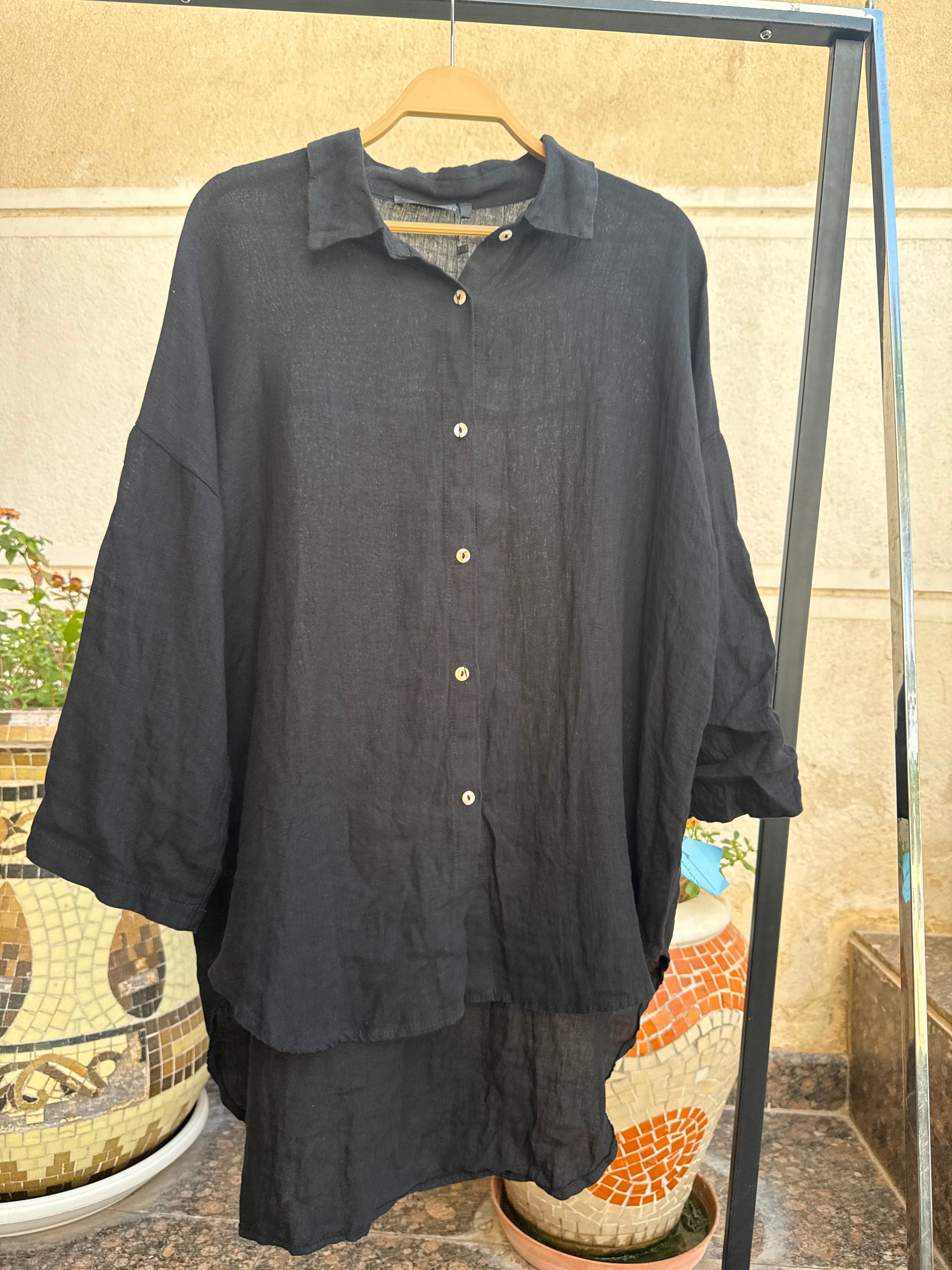 Amenaa linen shirt displayed on a hanger, featuring a lightweight, breathable fabric with a classic collar and button-down design.