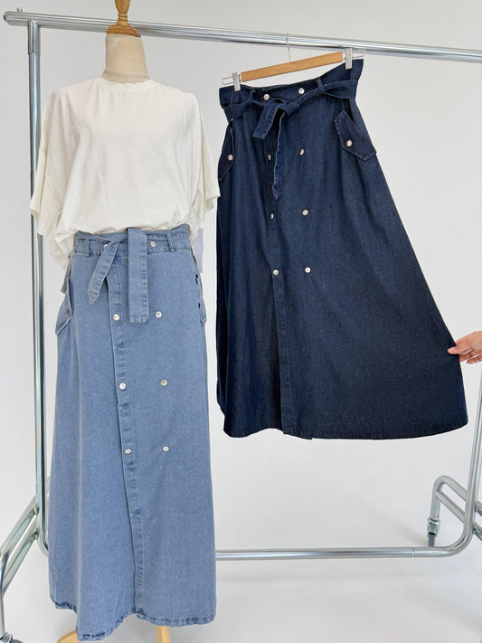 Amenaa button denim skirt shown hanging with front view, featuring metal buttons and classic blue denim fabric.