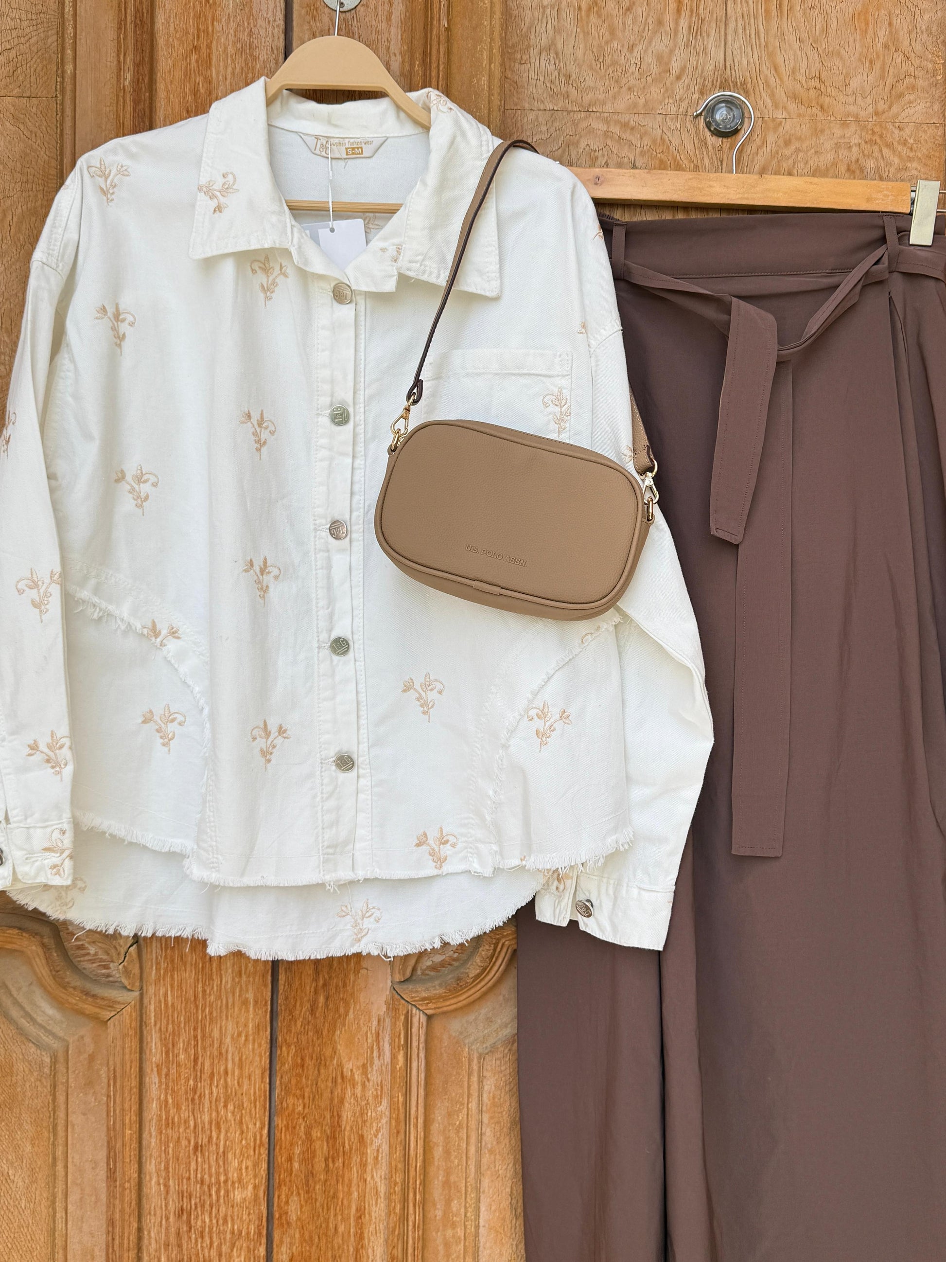 Flowery embroidered Amenaa gabardine jacket with colorful floral patterns and tailored fit, displayed on a hanger.