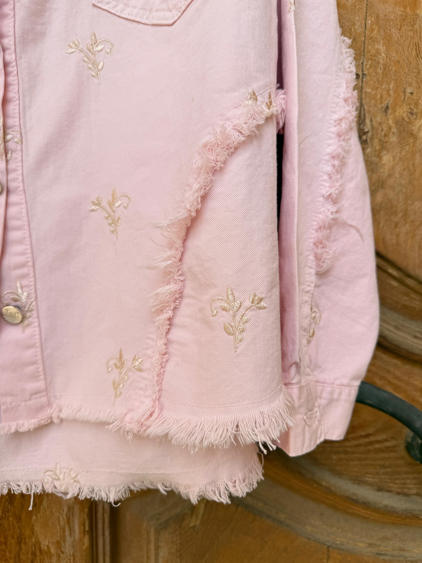 Flowery embroidered gabardine jacket by Amenaa featuring colorful floral patterns and tailored fit, displayed on a hanger.