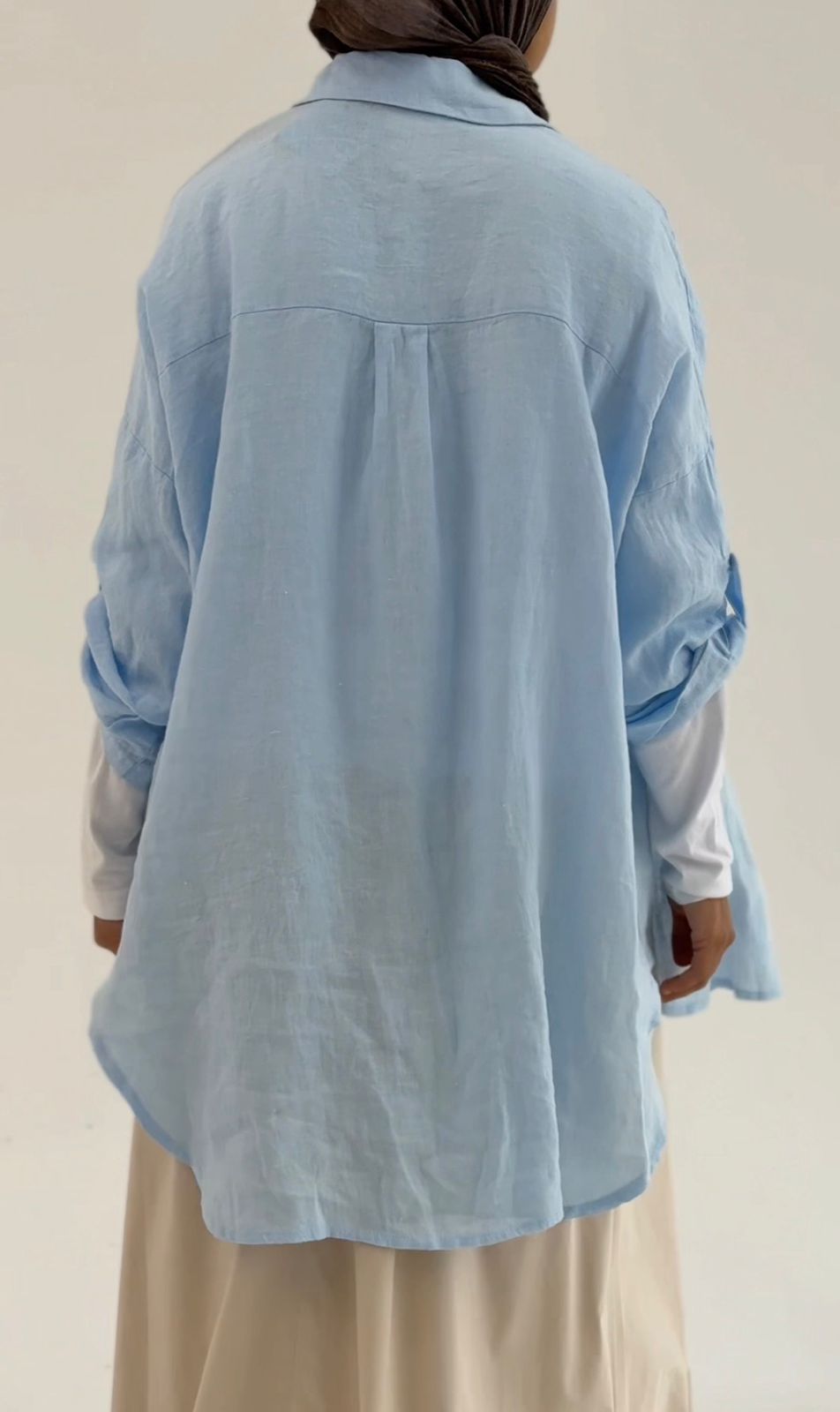 Light beige linen shirt by Amenaa displayed on a hanger, showcasing the relaxed fit and breathable fabric perfect for casual wear.