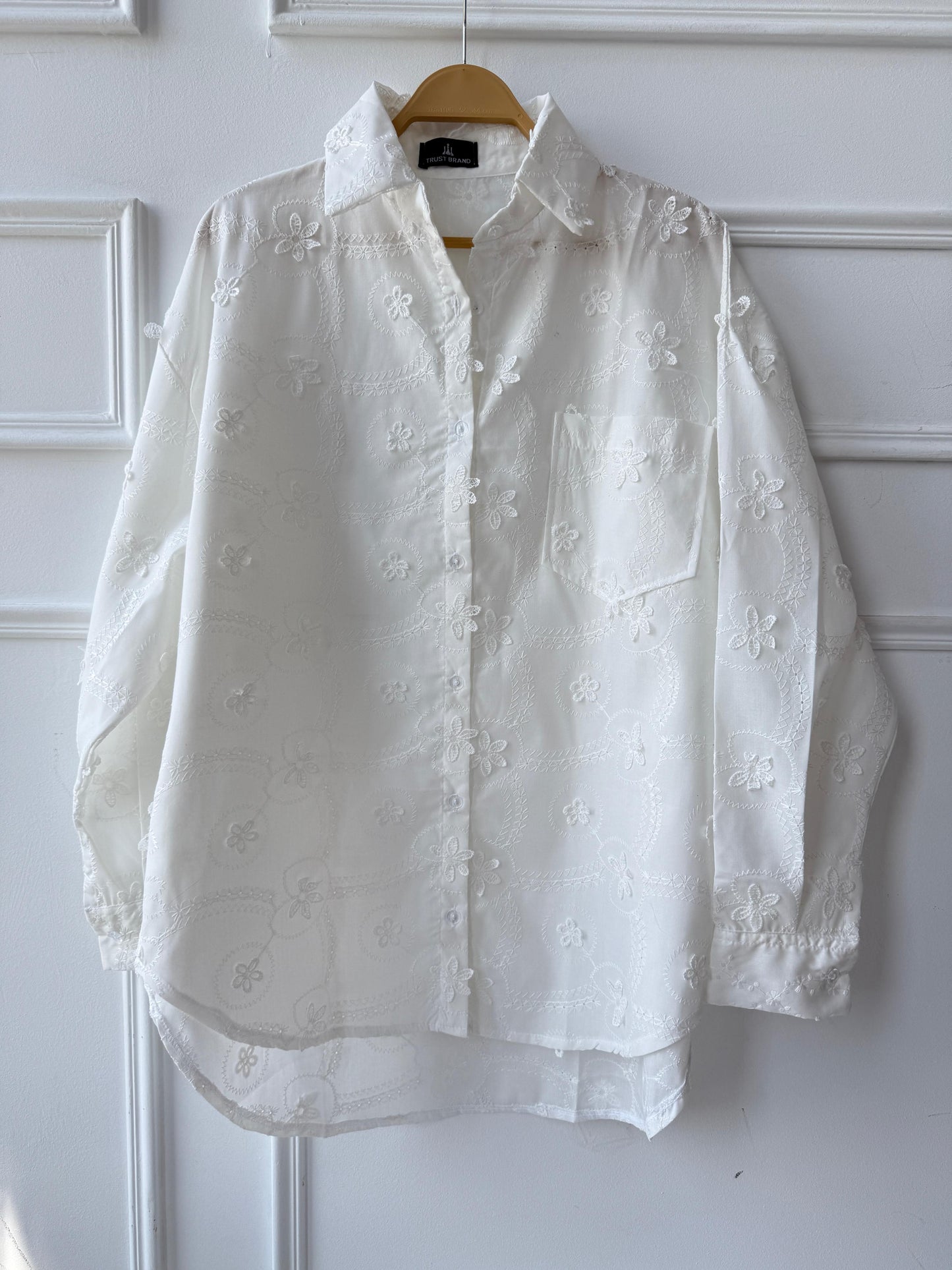 Floral embroidered Amenaa shirt with intricate flower patterns and lightweight fabric, showcased on a hanger.