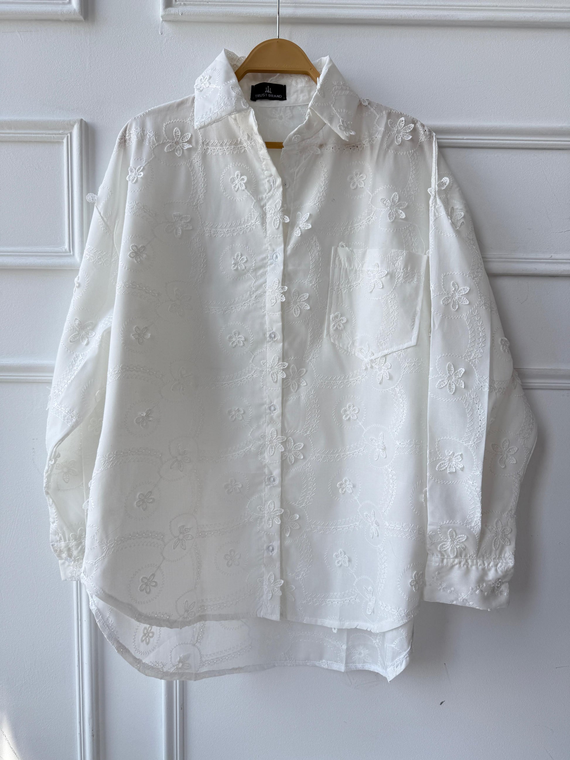 Floral embroidered Amenaa shirt with intricate flower patterns and lightweight fabric, showcased on a hanger.