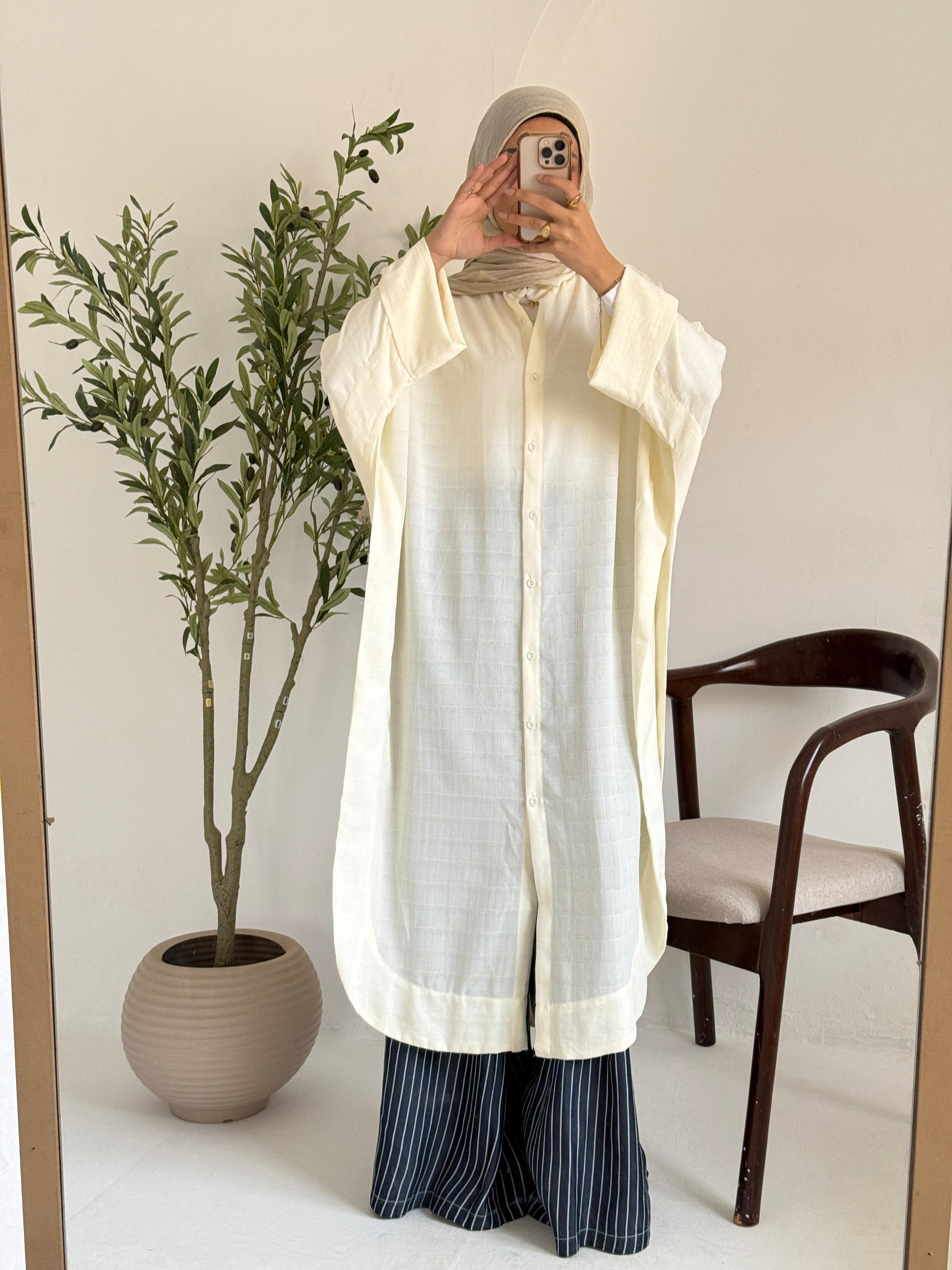 Amenaa textured oversized shirt dress hanging on a wooden hanger, showcasing its relaxed fit and fabric details.