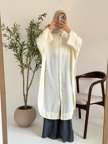 Amenaa textured oversized shirt dress hanging on a wooden hanger, showcasing its relaxed fit and fabric details.