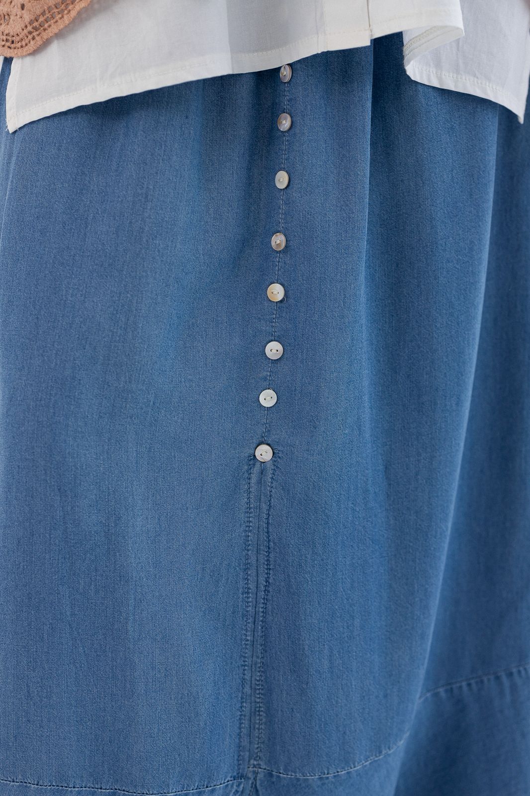 Light denim skirt by Amenaa with a stylish fit, displayed on a hanger showing the fabric texture and classic denim details.
