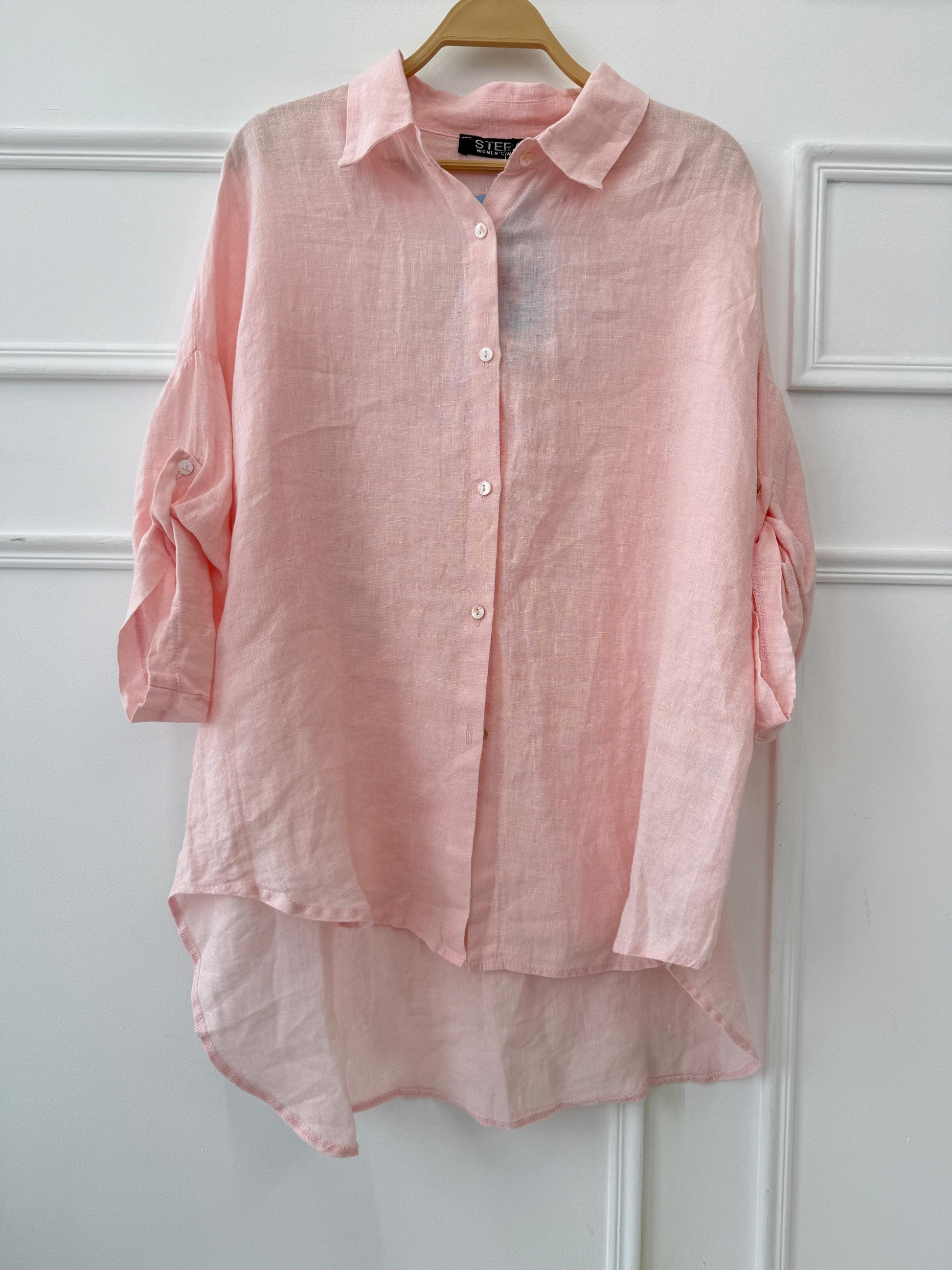 Light beige linen shirt by Amenaa displayed on a hanger, showing its relaxed fit and textured fabric for casual summer style.