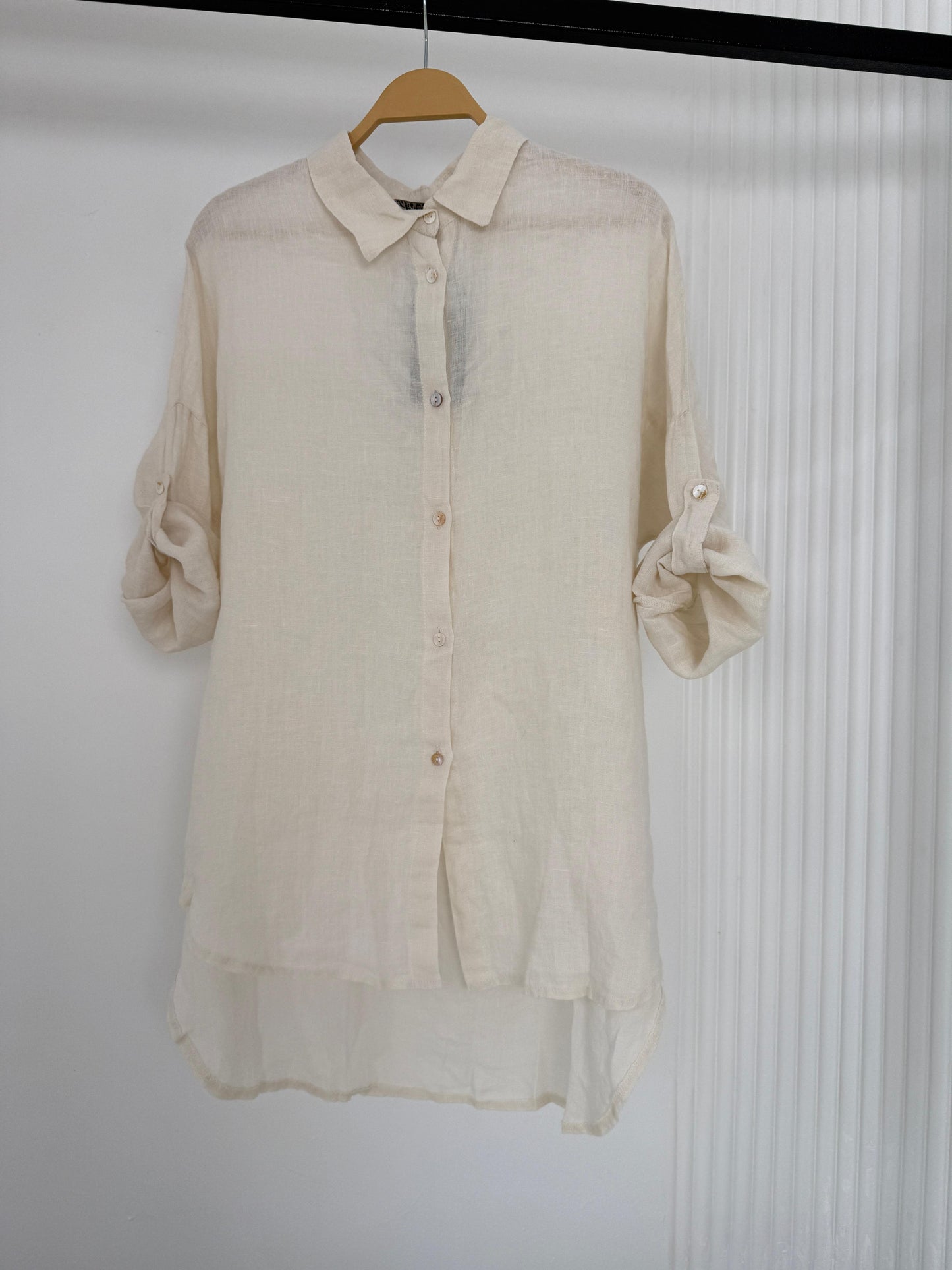 Amenaa linen shirt displayed on a hanger, featuring a lightweight, breathable fabric with a classic collar and button-down front.