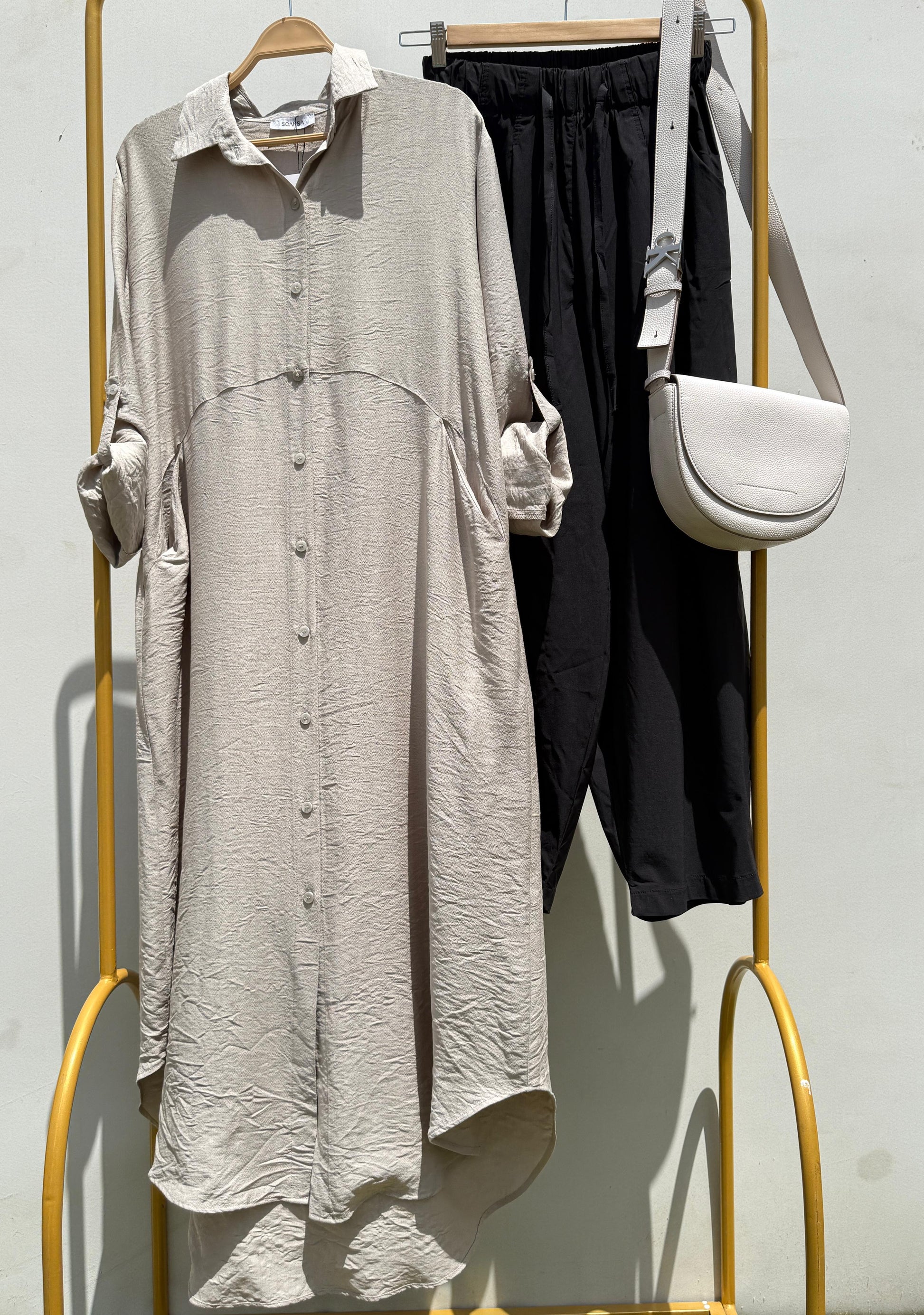 Amenaa shirt dress with short sleeves, button front, and waist tie, shown on a model in a casual indoor setting.
