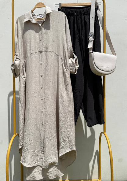 Amenaa shirt dress with short sleeves, button front, and waist tie, shown on a model in a casual indoor setting.