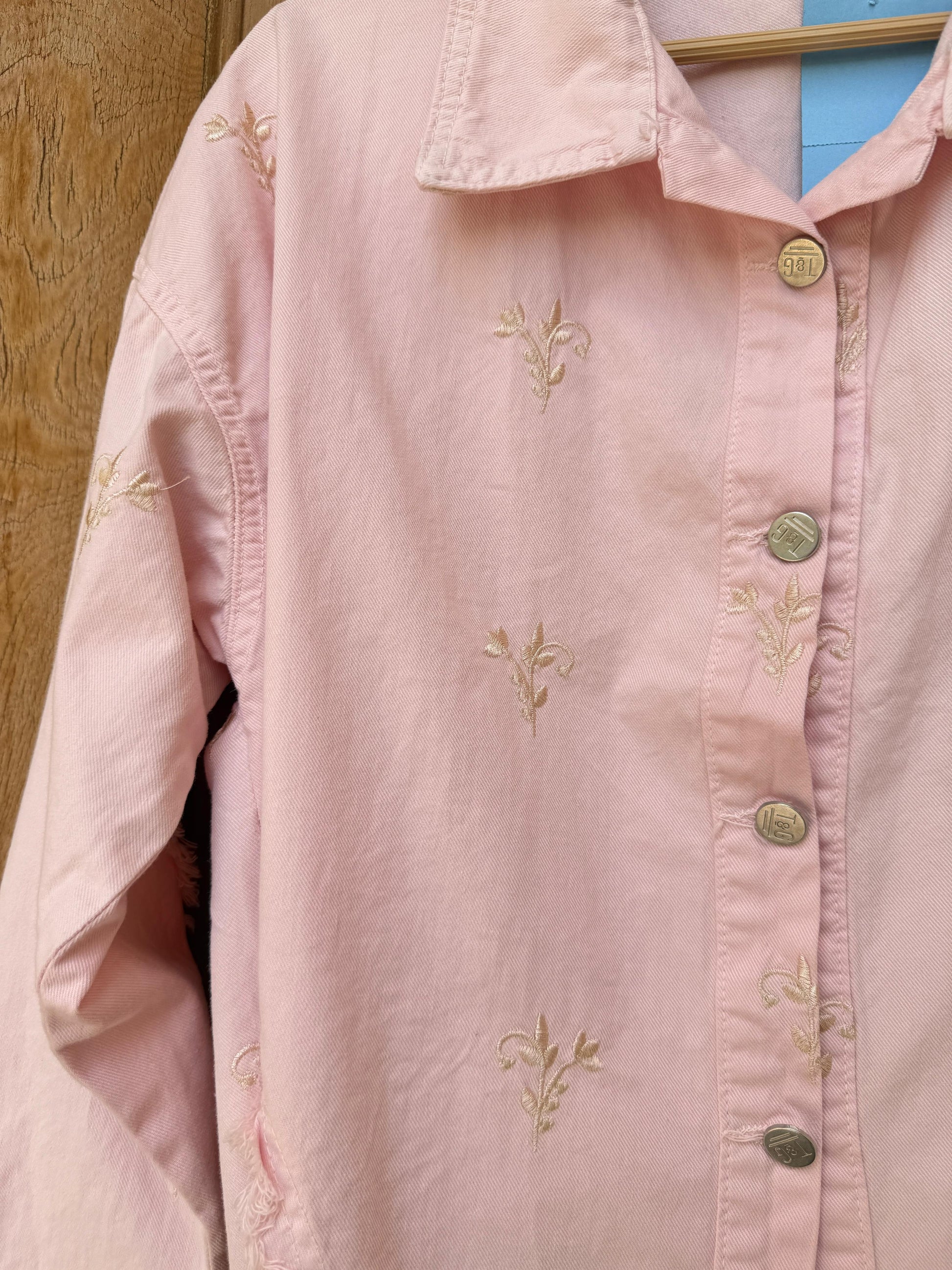 Flowery embroidered Amenaa gabardine jacket with colorful floral patterns and tailored fit, displayed on a hanger.