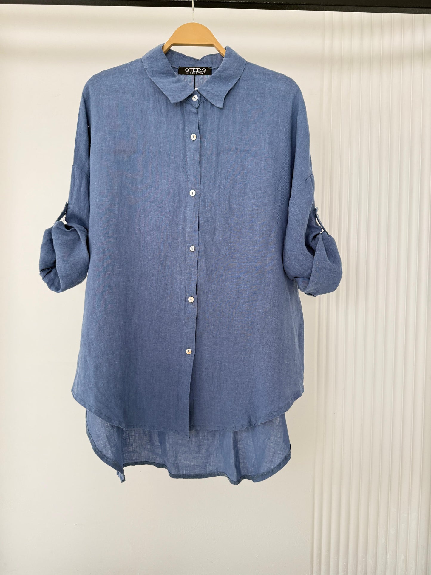 Amenaa linen shirt displayed on a hanger, showcasing lightweight, breathable fabric with a relaxed fit in natural linen material.