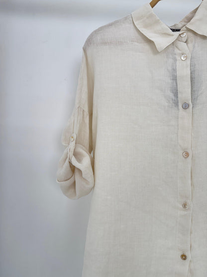 Amenaa linen shirt displayed on a hanger, showcasing lightweight, breathable fabric with a classic collar and button front design.