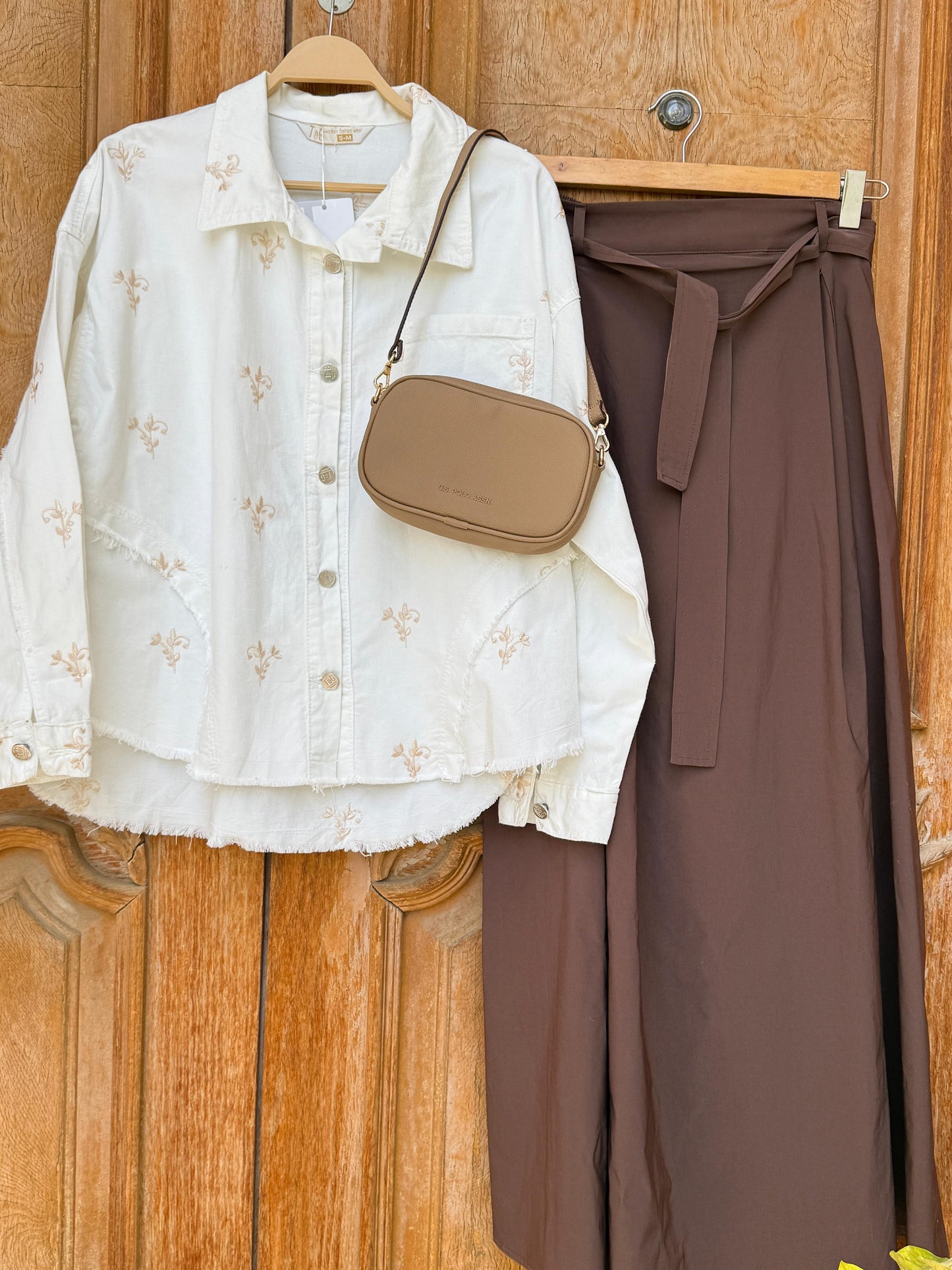 Flowery embroidered gabardine jacket by Amenaa with colorful floral patterns and tailored fit, displayed on a hanger.