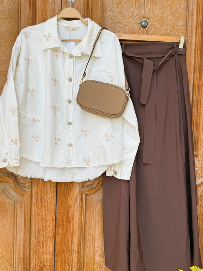 Flowery embroidered gabardine jacket by Amenaa with colorful floral patterns and tailored fit, displayed on a hanger.